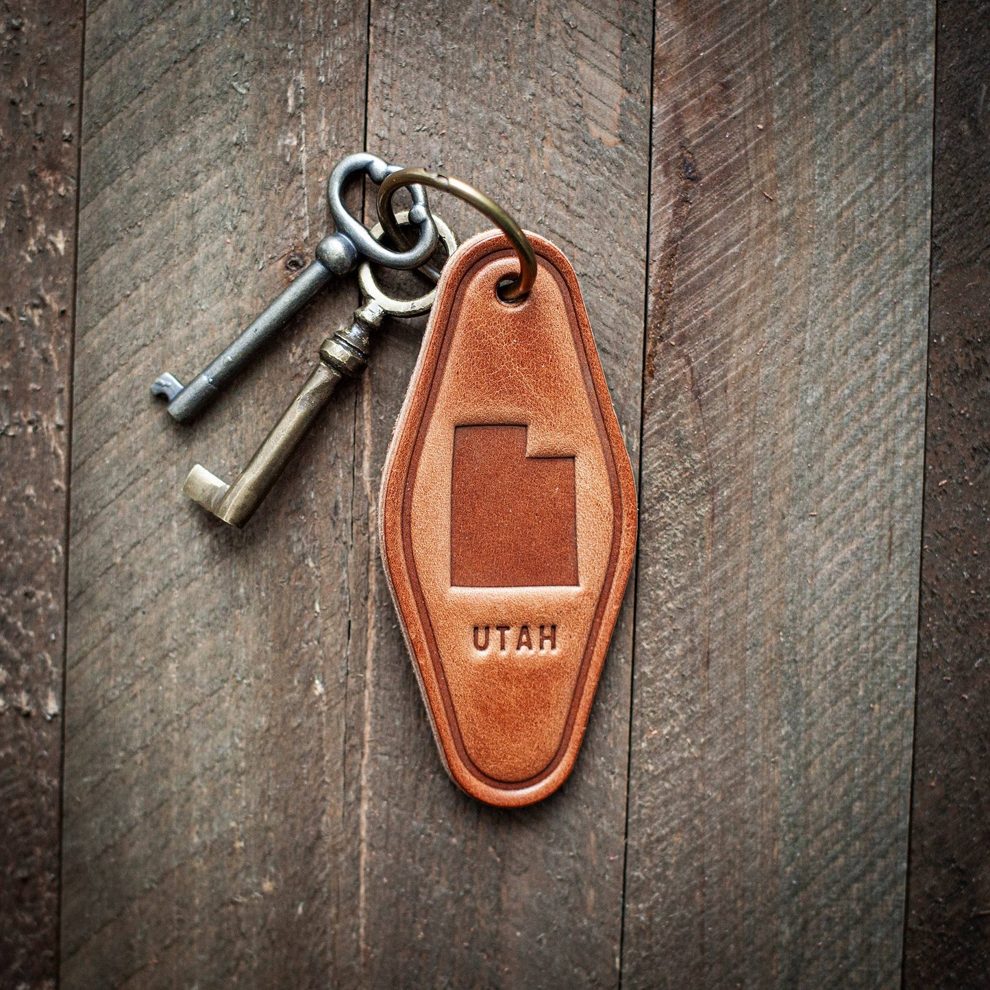 Leather keychain with 'UTAH' engraving on a wooden surface