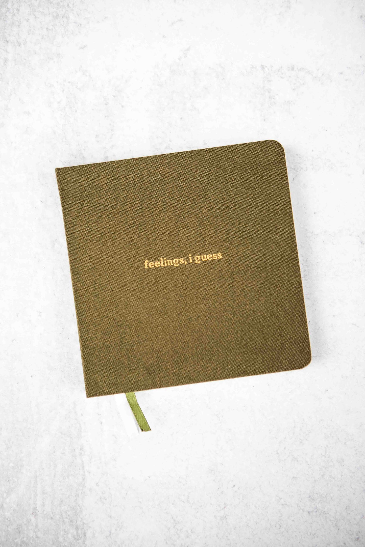 olive colored notebook with embossed 'feelings, i guess' text on a white background