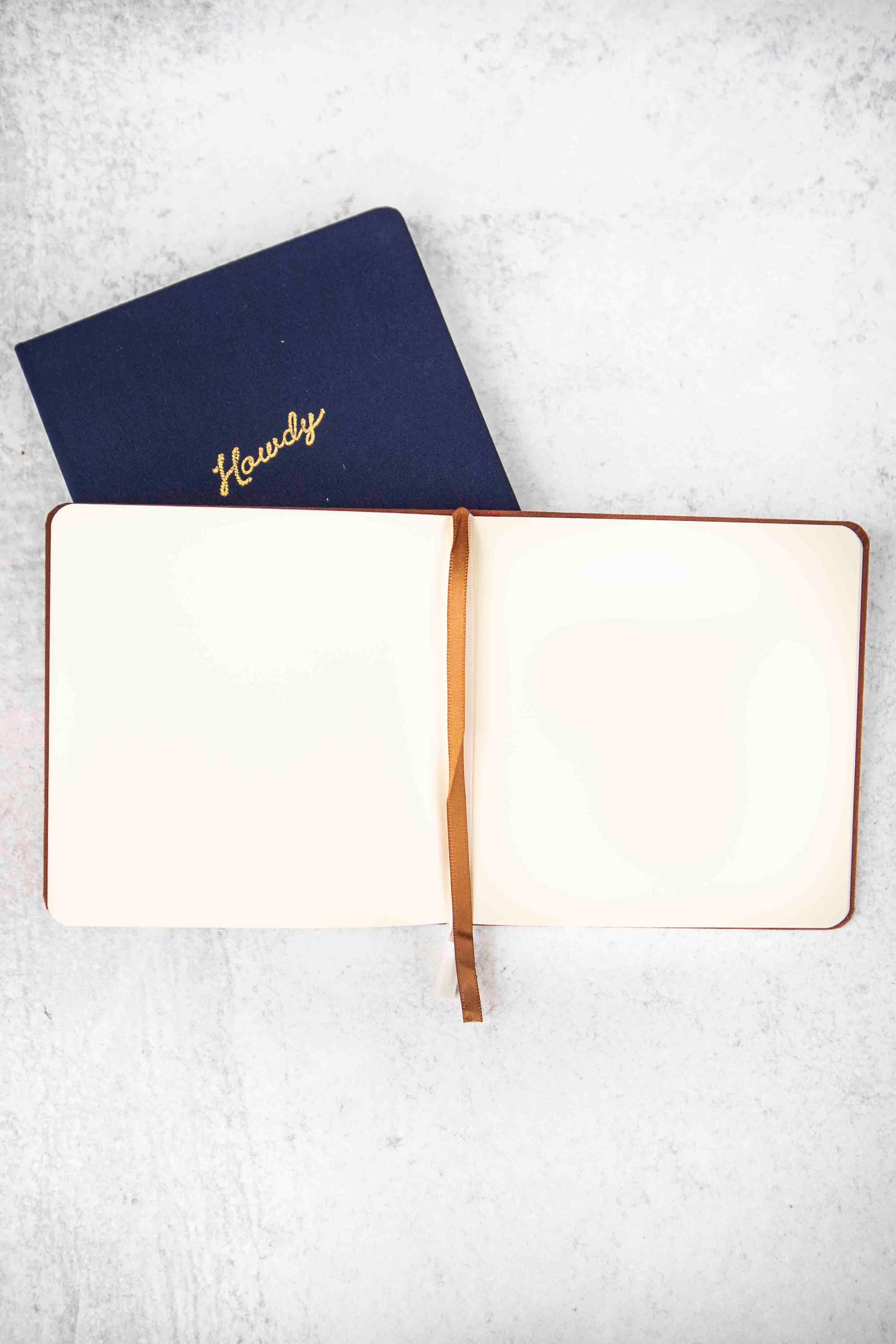 Open notebook with a brown strap on a light gray background