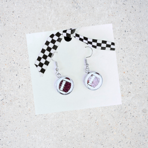 Football earrings on a white card with a gray background