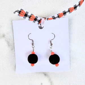 Black fuzzy circle Halloween earrings on a marble background