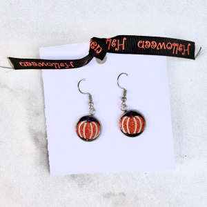 Pumpkin-shaped glitter earrings on a white card with a Halloween ribbon
