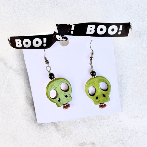 Green skull-shaped earrings on a white card with 