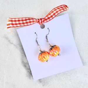 Pair of orange pumpkin-shaped earrings on a white card with an orange and white checkered ribbon.