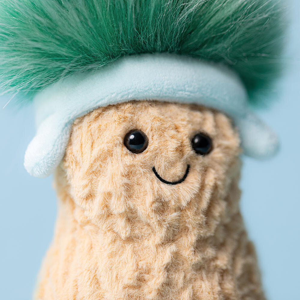 Plush toy peanut with a green hair and blue headband on a light blue background