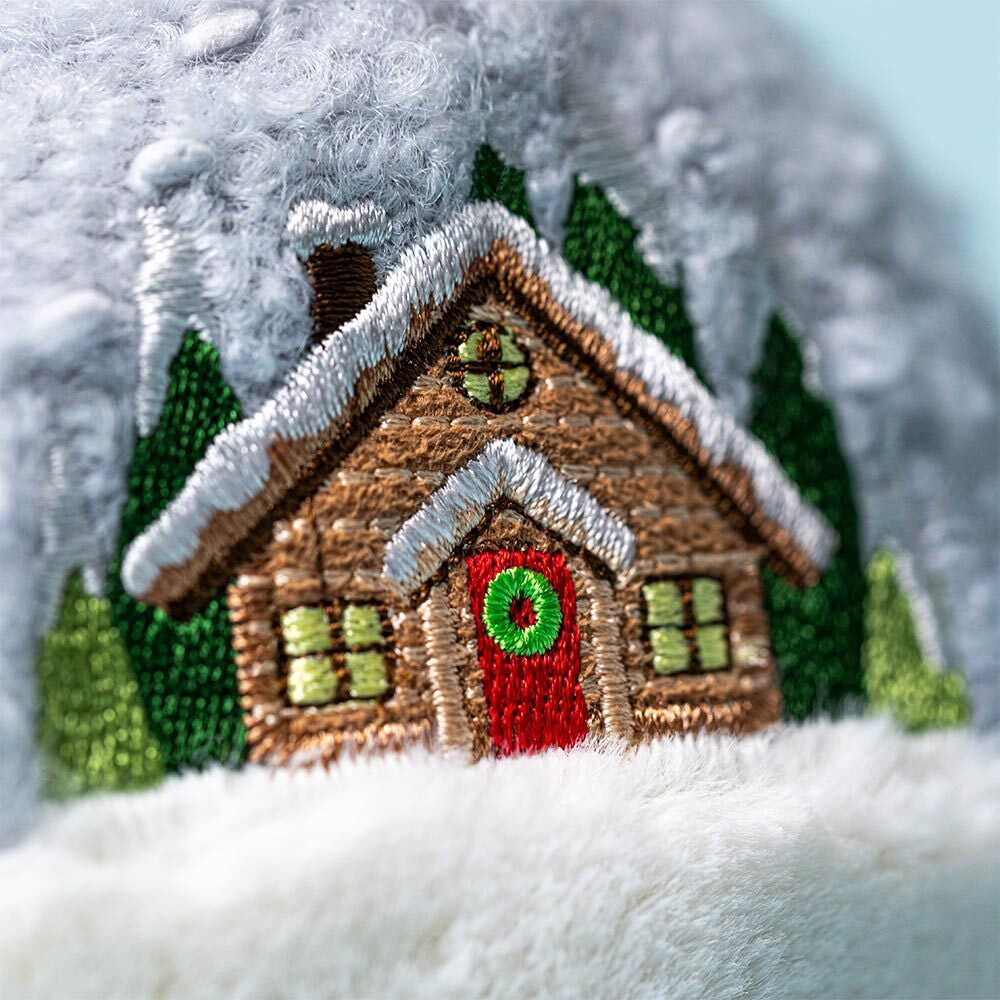 Embroidered wooden cabin with a red door and green windows on a snowy background