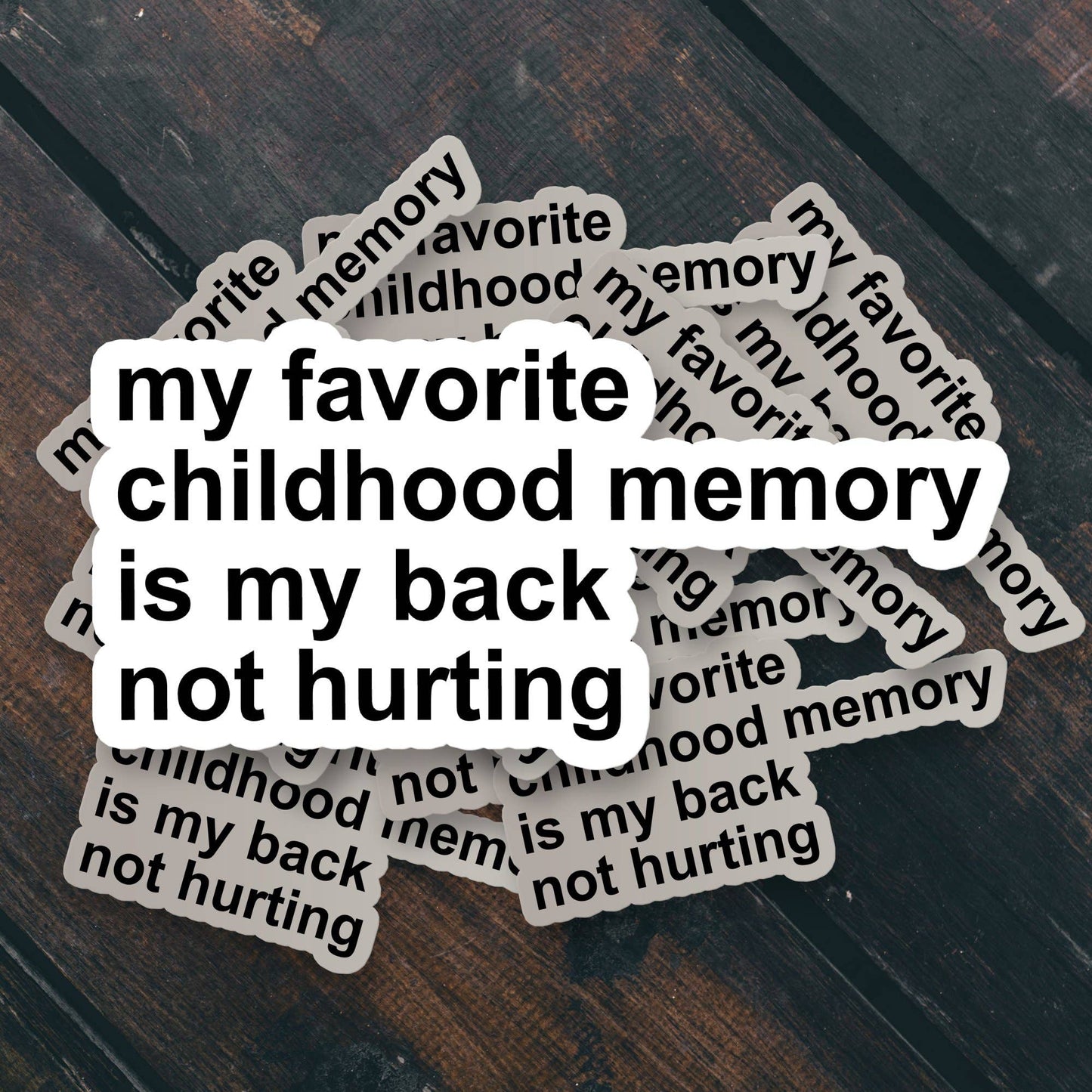 Stack of stickers with the text 'my favorite childhood memory is my back not hurting' on a wooden surface.