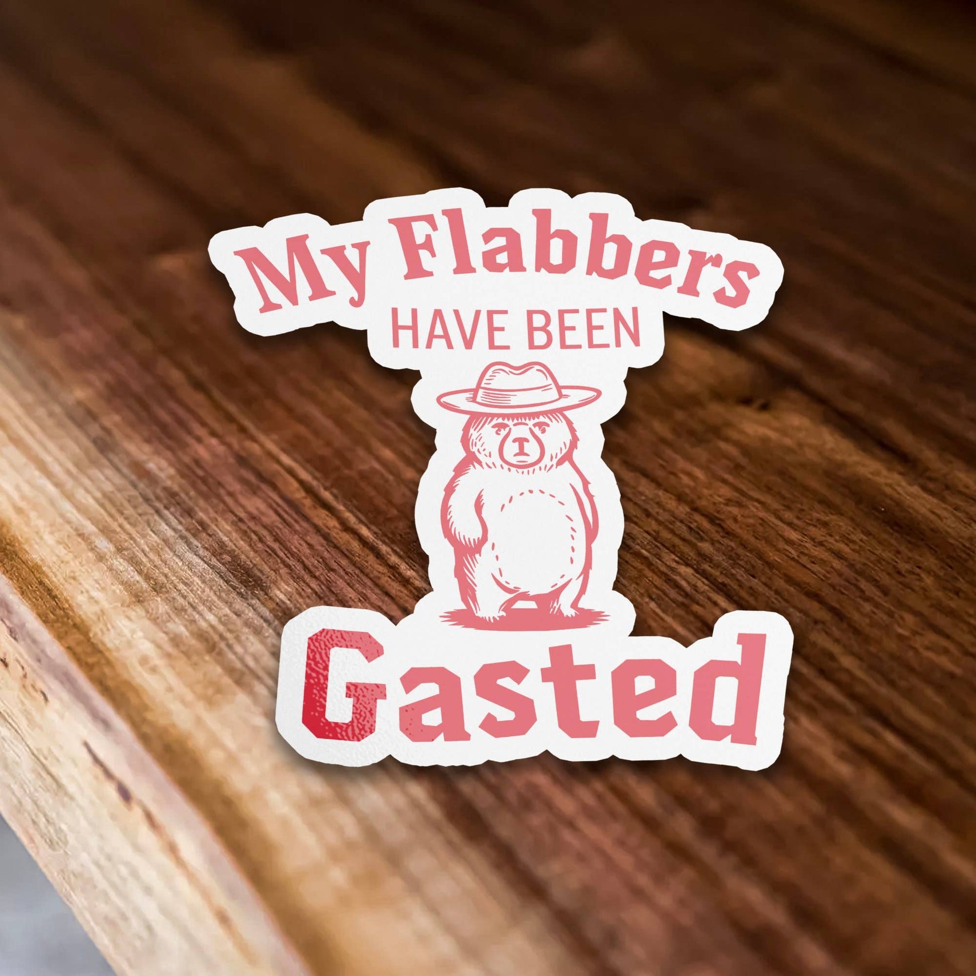 Sticker with a bear wearing a hat and the text 'My Flabbers HAVE BEEN Gasted' on a wooden surface
