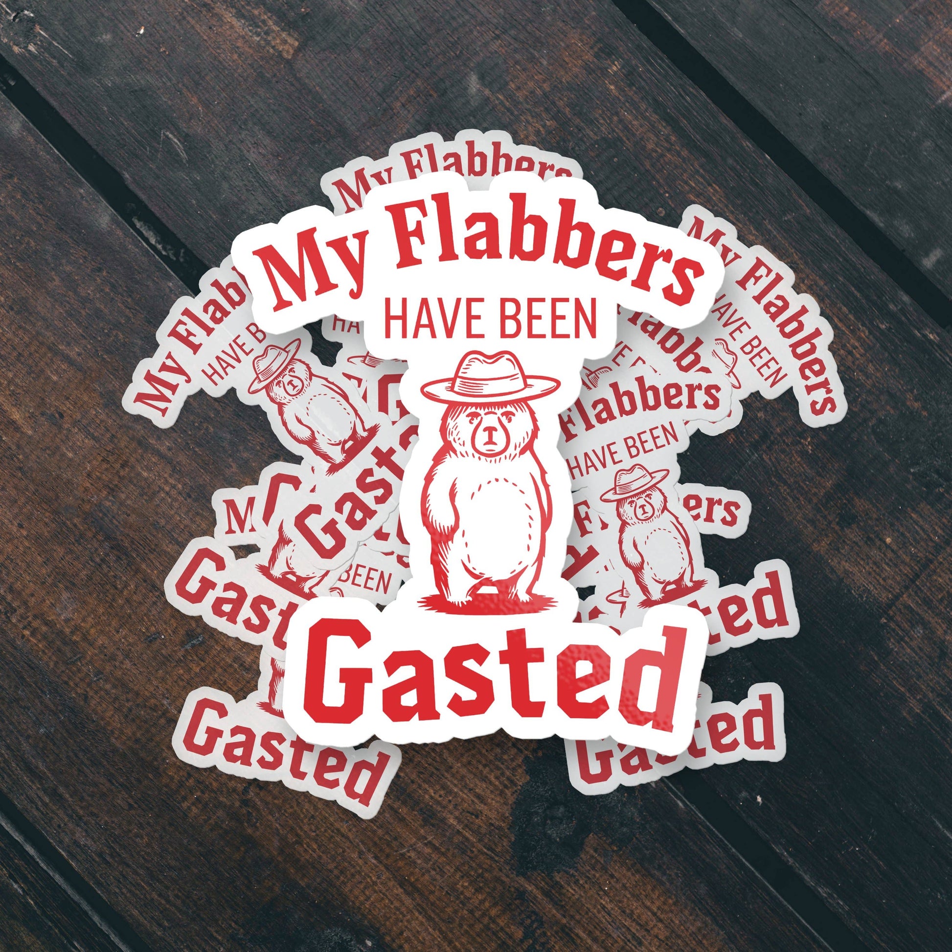 Sticker set witha bear wearing a hat and text saying 'My Flabbers Have Been Gasted' text on a wooden surface
