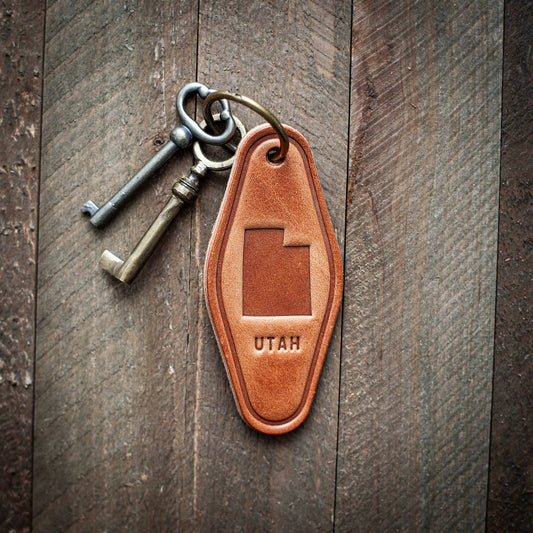Leather keychain with 'UTAH' engraving on a wooden surface