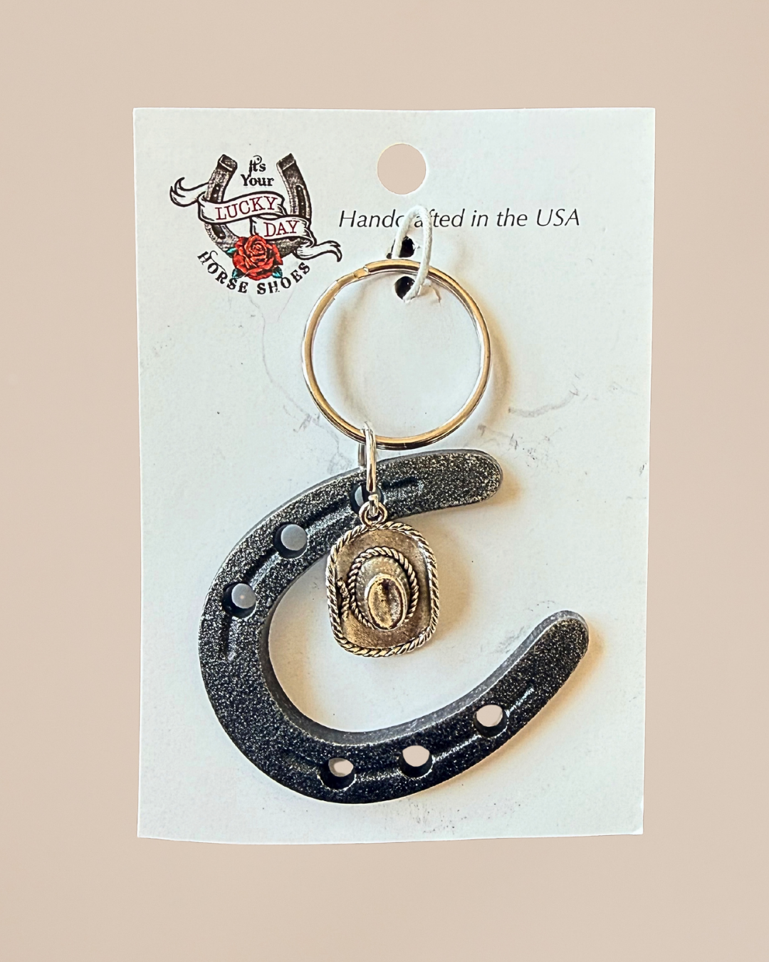 Keychain with horseshoe and key ring on a white card with branding text.
