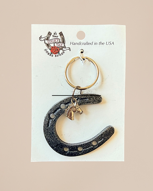 Horseshoe keychain with pendant on a white card with branding text