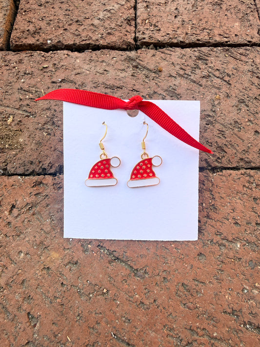 Red and white earrings on a card with a red ribbon, placed on a stone surface.
