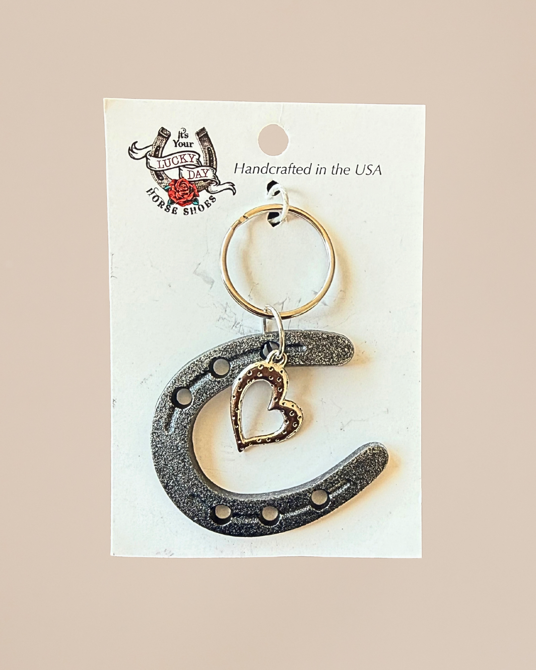 Keychain with horseshoe and heart design on a beige card with 'Lucky Day' branding.
