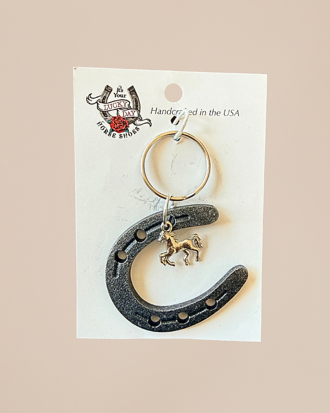 Horseshoe keychain with horse charm on a white card with branding