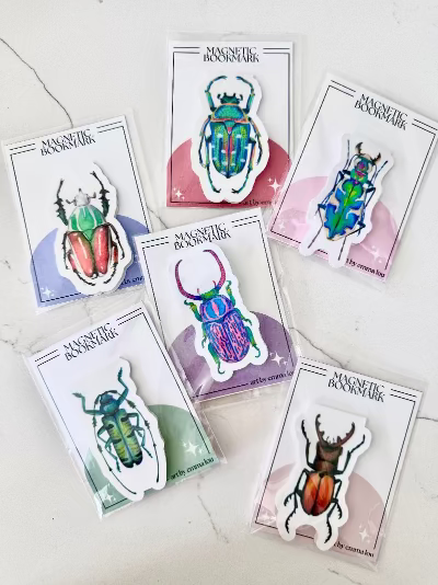 Set of 6 colorful beetle-shaped magnetic bookmarks on white cards.